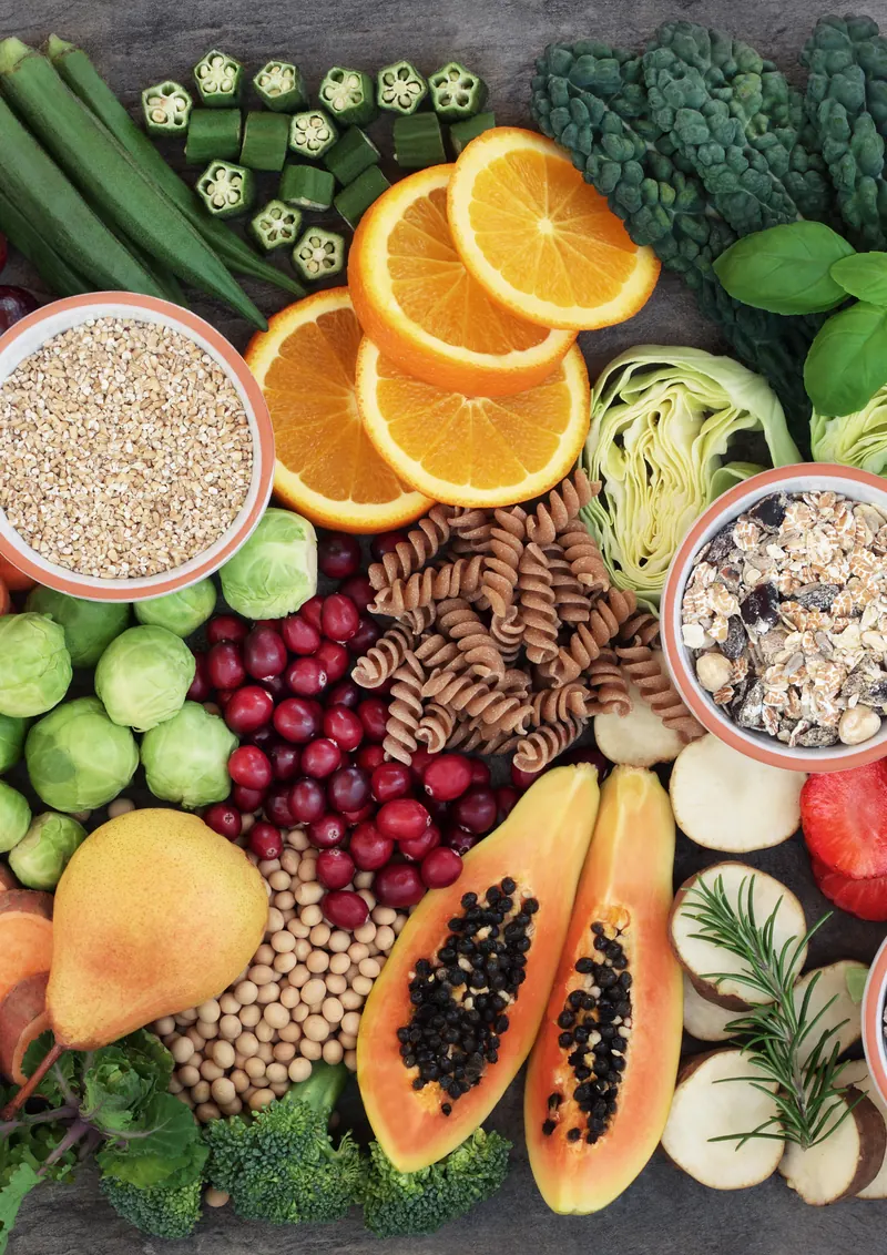 Fresh vegetables, fruits, grains and legumes arranged on a dark table: fiber ingredients